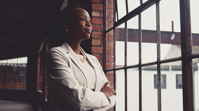 Confident Businesswoman Looking Through Window in Modern Industrial Office 