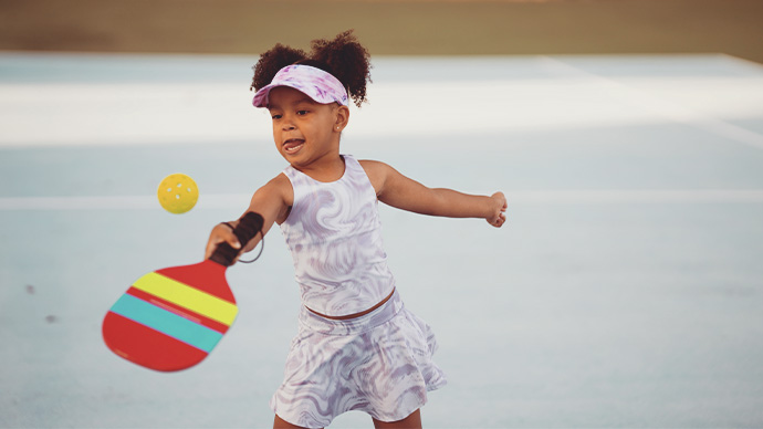 Hispanic girl returning a server at pickle ball practice