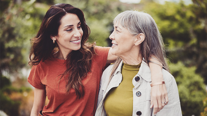 Smiling woman talking with her senior mom while walking outside
