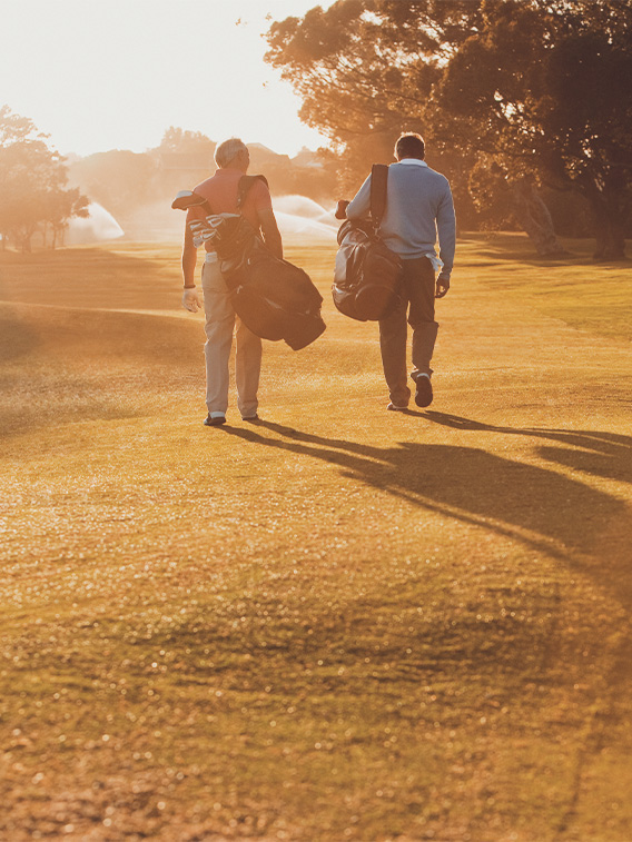 Men carrying golf bags on golf course