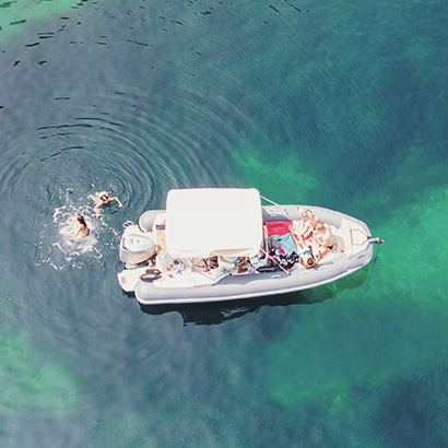 Aerial view of a family with children relaxing on a boat in the blue turquoise sea. Top view. Amazing nature background. The color of the water and beautifully bright. Fresh freedom. Adventure day.